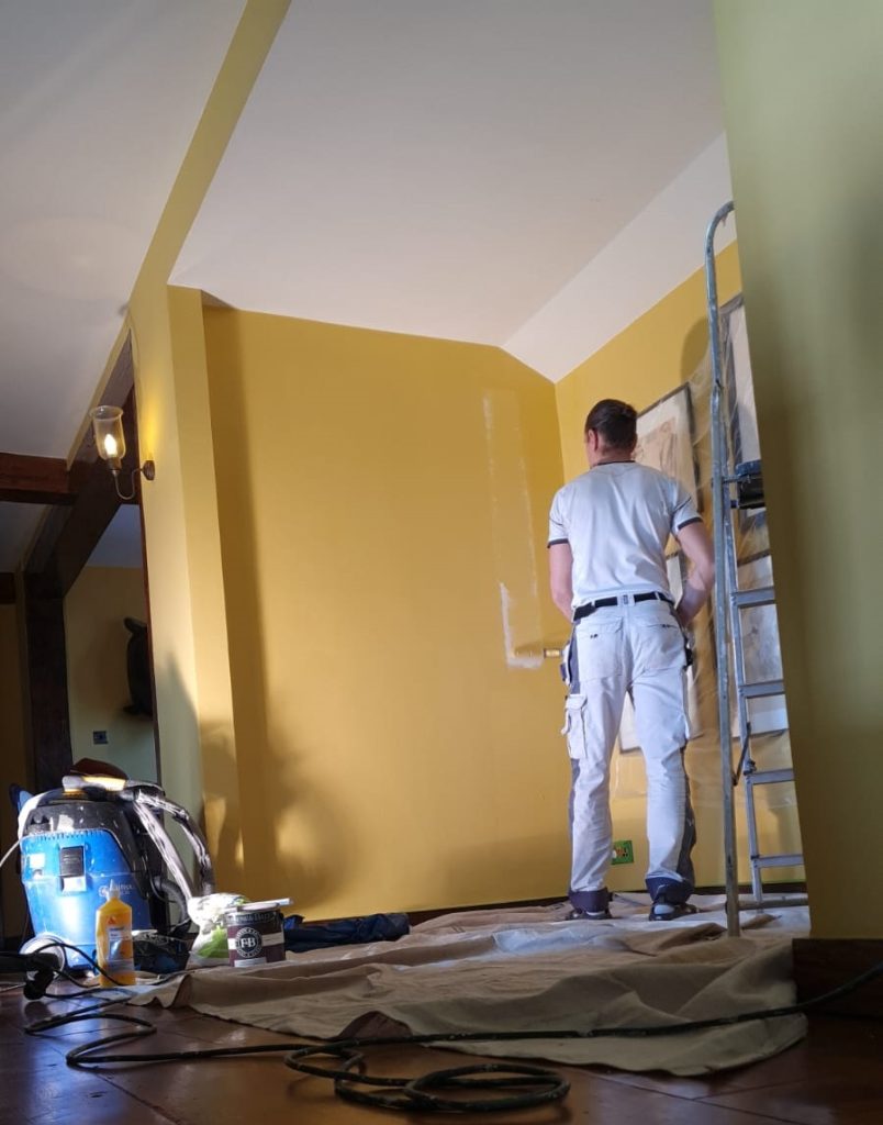 Decorator rolling fresh paint onto a living room wall