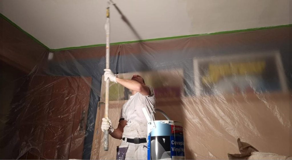 Painter spray-painting a ceiling during interior decorating